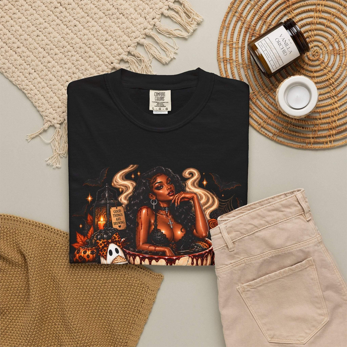 Unisex Garment-Dyed T-shirt in black with bold Halloween graphic featuring a stylish woman, skull mug, pumpkins, ghosts, and bats